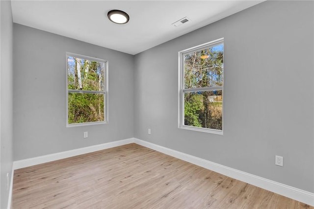 empty room with light wood-type flooring, visible vents, and baseboards