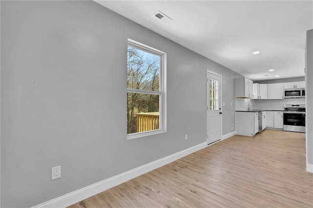 kitchen featuring a sink, visible vents, baseboards, appliances with stainless steel finishes, and light wood-type flooring