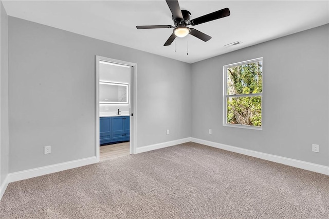 unfurnished room featuring baseboards, visible vents, a ceiling fan, and light colored carpet