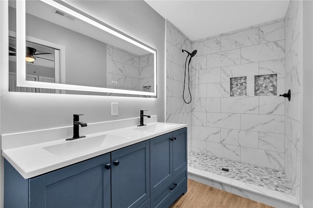 full bathroom with double vanity, visible vents, a sink, and tiled shower