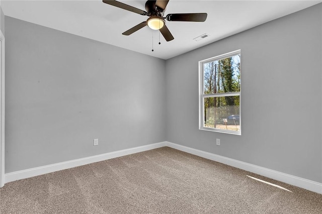 carpeted spare room featuring a ceiling fan, visible vents, and baseboards