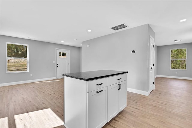 kitchen with light wood-type flooring, open floor plan, visible vents, and baseboards