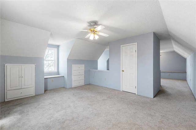 bonus room with a ceiling fan, lofted ceiling, light carpet, and a textured ceiling