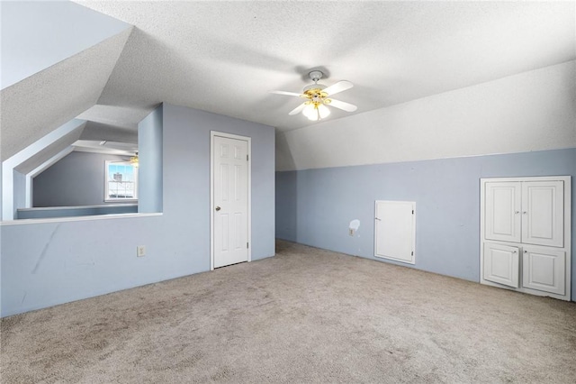 bonus room featuring a textured ceiling, a ceiling fan, and light colored carpet