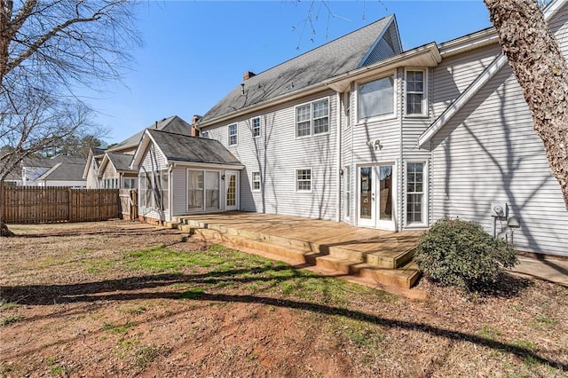 rear view of property with a deck, french doors, a lawn, and fence