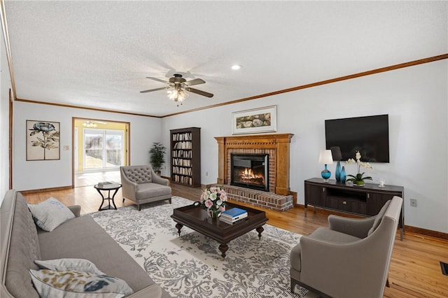 living area with ornamental molding, a fireplace, and light wood-style flooring