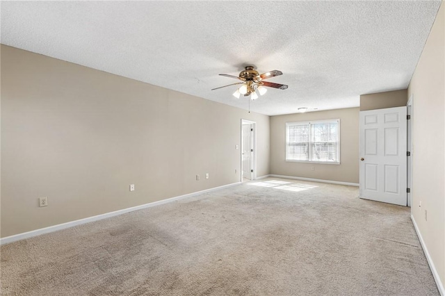 spare room with light carpet, a textured ceiling, baseboards, and a ceiling fan