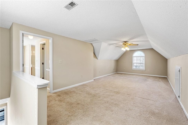 bonus room featuring baseboards, visible vents, light colored carpet, lofted ceiling, and a textured ceiling