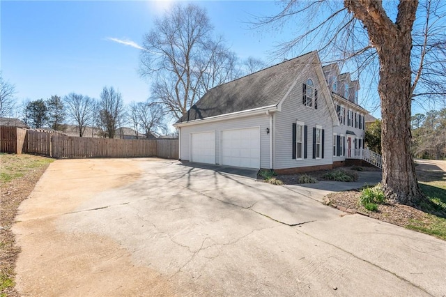 view of home's exterior with a garage, concrete driveway, and fence