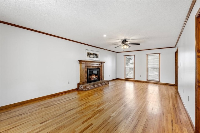 unfurnished living room featuring a ceiling fan, a brick fireplace, a textured ceiling, light wood-type flooring, and baseboards