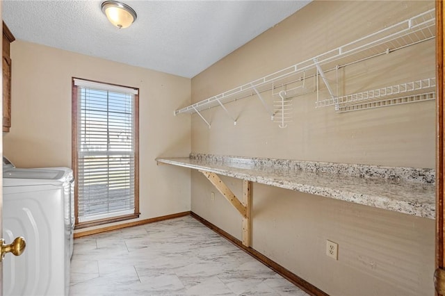 clothes washing area featuring a textured ceiling, laundry area, separate washer and dryer, baseboards, and marble finish floor