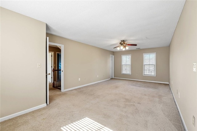 unfurnished room with ceiling fan, a textured ceiling, baseboards, and light colored carpet