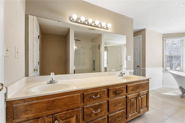 full bathroom with double vanity, wainscoting, tile patterned floors, a textured ceiling, and a sink