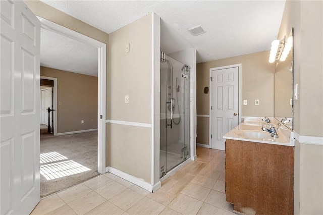 bathroom featuring double vanity, visible vents, a sink, a shower stall, and a textured ceiling