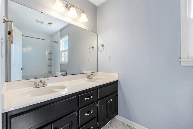 full bathroom with toilet, double vanity, a sink, and visible vents