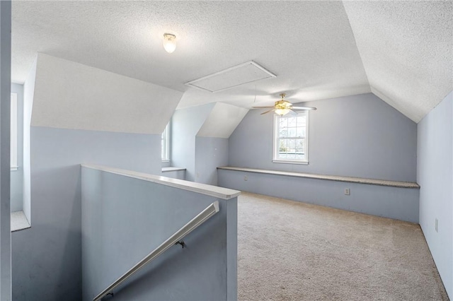 bonus room with vaulted ceiling, a textured ceiling, carpet flooring, and attic access