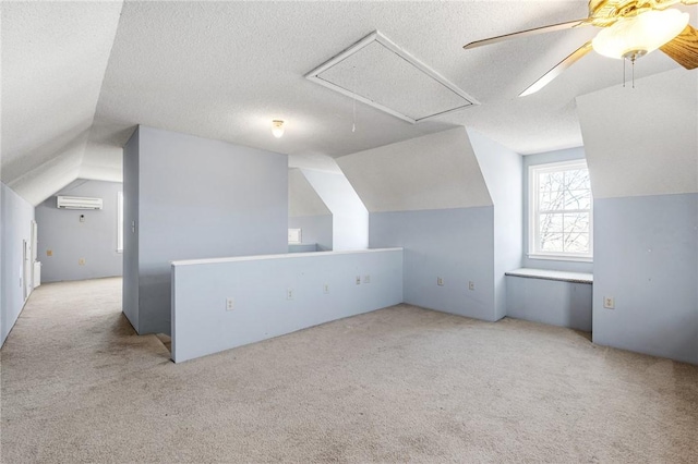 additional living space featuring a textured ceiling, an AC wall unit, light carpet, and attic access