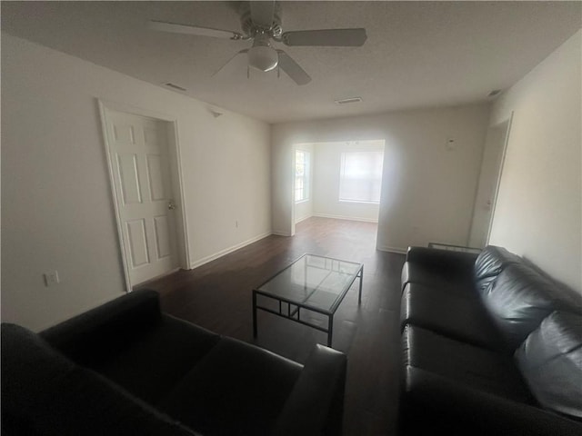 living room featuring baseboards, dark wood-style flooring, visible vents, and a ceiling fan