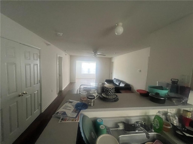 kitchen with light countertops, dark wood-type flooring, a sink, and a ceiling fan