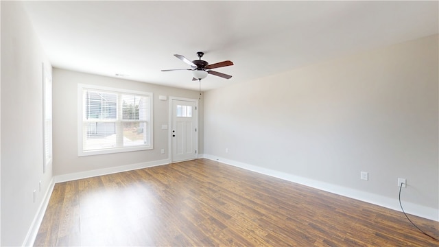 spare room with baseboards, dark wood finished floors, and a ceiling fan