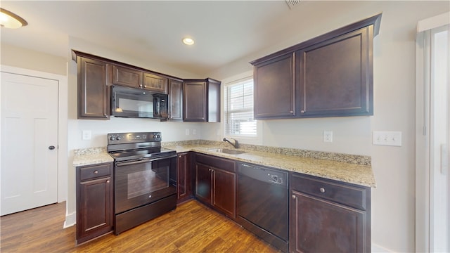 kitchen featuring dark wood-type flooring, a sink, black appliances, and light stone countertops