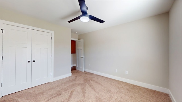 unfurnished bedroom with a ceiling fan, a closet, light colored carpet, and baseboards