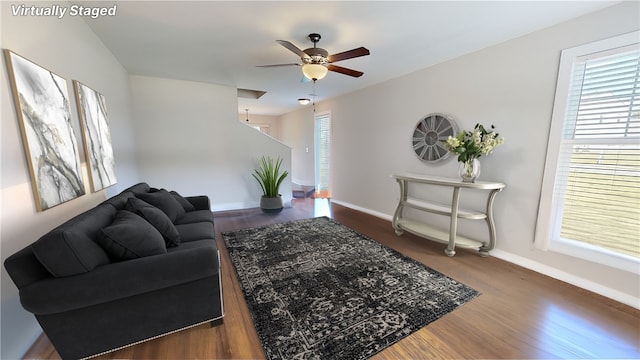 living area featuring baseboards, dark wood finished floors, and a ceiling fan