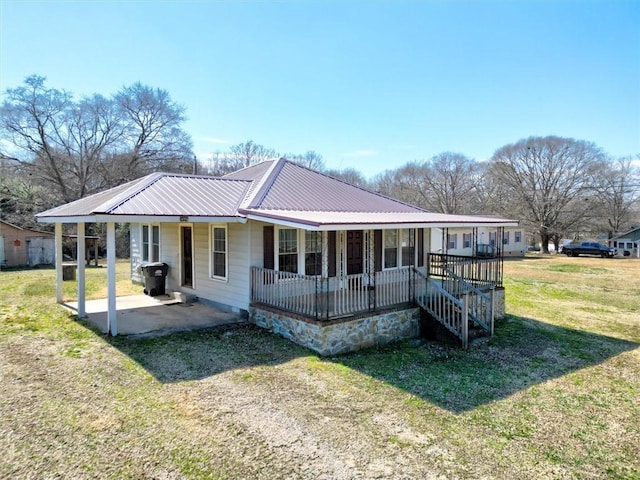 view of front of property featuring covered porch, metal roof, a patio, and a front yard