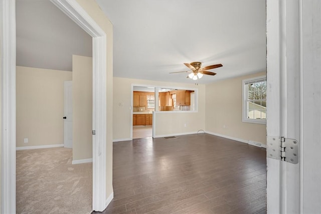 unfurnished living room with ceiling fan, visible vents, baseboards, and wood finished floors