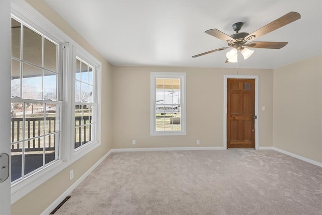 unfurnished room with light carpet, ceiling fan, plenty of natural light, and baseboards