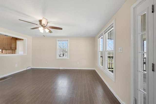 empty room with dark wood-style floors, a healthy amount of sunlight, and baseboards