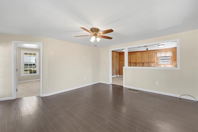 unfurnished living room with plenty of natural light, baseboards, and dark wood-type flooring