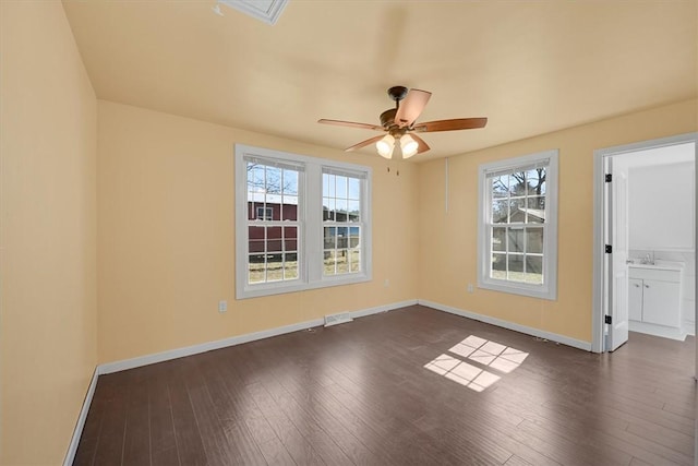 unfurnished room with a wealth of natural light, baseboards, and dark wood-style flooring