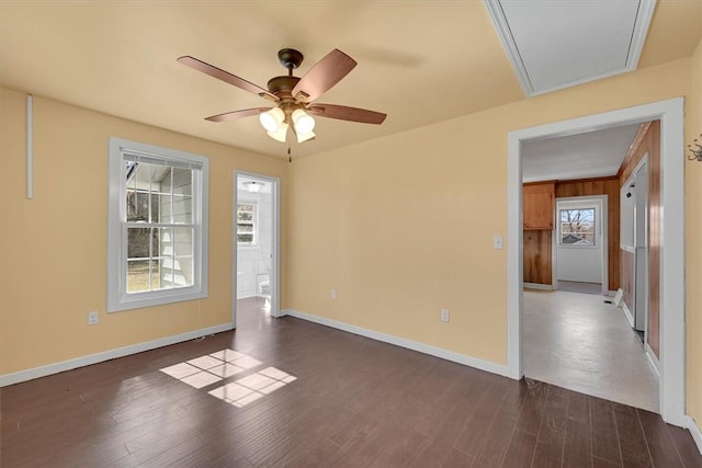 spare room with dark wood-style floors, attic access, baseboards, and ceiling fan