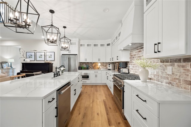 kitchen featuring custom range hood, high quality appliances, glass insert cabinets, hanging light fixtures, and white cabinetry