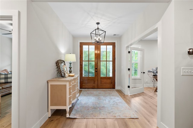 foyer with light wood-style flooring, a notable chandelier, visible vents, baseboards, and french doors