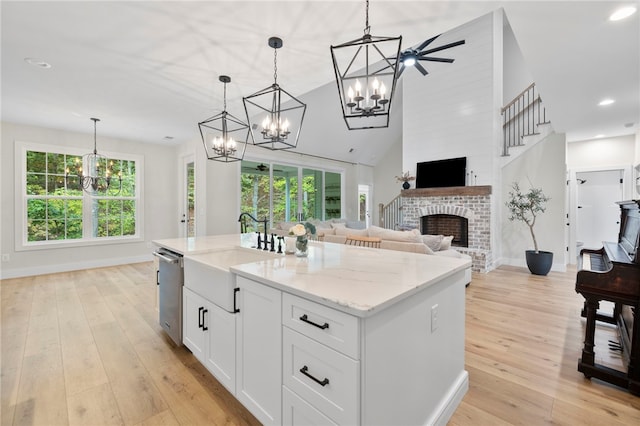 kitchen with open floor plan, a center island with sink, white cabinets, and pendant lighting