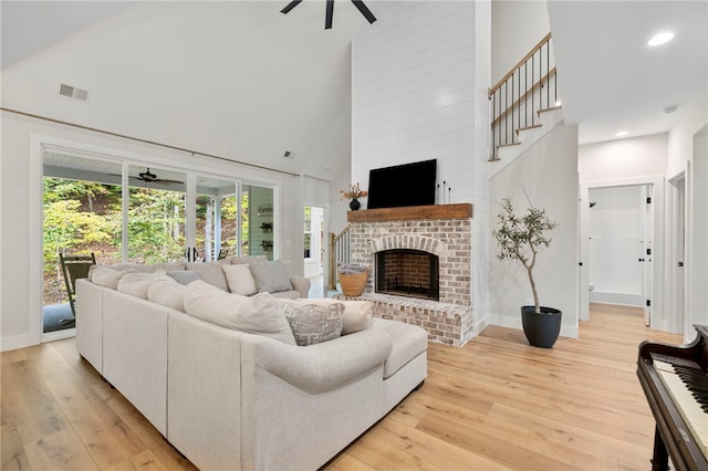 living area with a towering ceiling, light wood-type flooring, ceiling fan, and visible vents