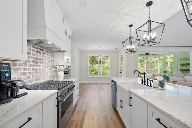 kitchen with premium range hood, appliances with stainless steel finishes, decorative light fixtures, and white cabinets