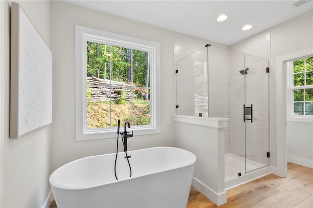 bathroom featuring recessed lighting, a soaking tub, a shower stall, wood finished floors, and baseboards