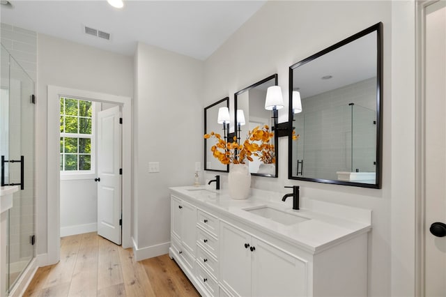 full bath featuring double vanity, visible vents, a sink, and wood finished floors