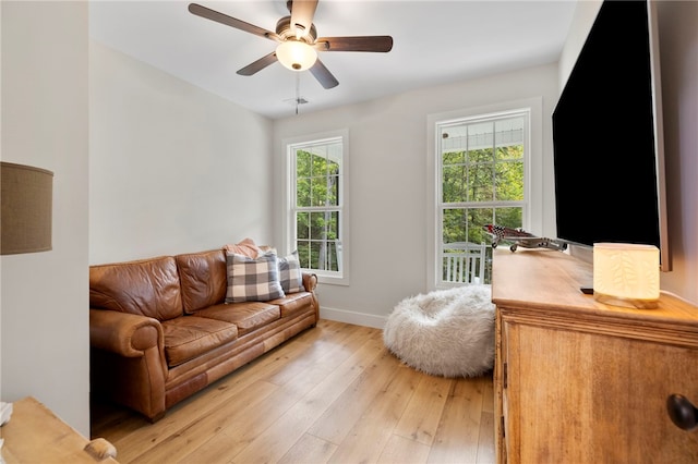 living area with light wood-style floors, baseboards, and a ceiling fan