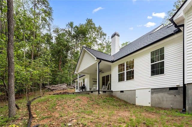 rear view of property with crawl space, ceiling fan, and a chimney