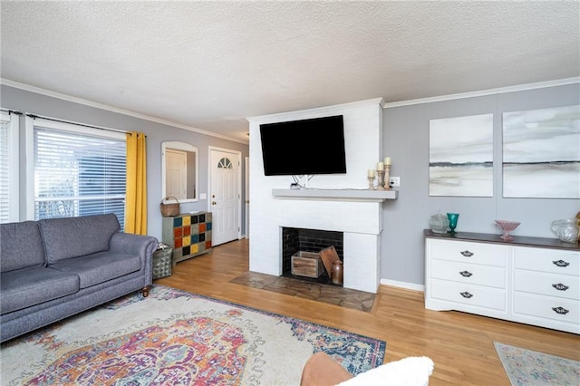 living room featuring a fireplace with flush hearth, crown molding, a textured ceiling, and light wood finished floors