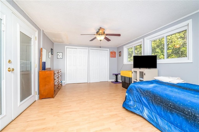 bedroom featuring light wood-type flooring, a textured ceiling, ceiling fan, and ornamental molding