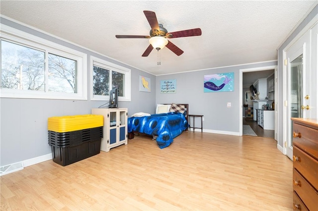 bedroom with light wood finished floors, visible vents, and a textured ceiling