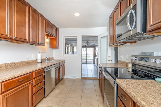 kitchen with light countertops, ornamental molding, light tile patterned floors, appliances with stainless steel finishes, and a ceiling fan