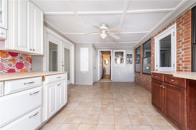 kitchen with white cabinets, brick wall, light countertops, light tile patterned floors, and ceiling fan