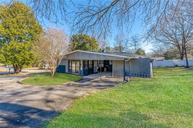 view of front of house with aphalt driveway, a carport, a front lawn, and fence