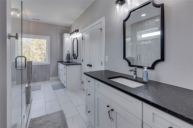 bathroom featuring marble finish floor, two vanities, visible vents, a stall shower, and a sink